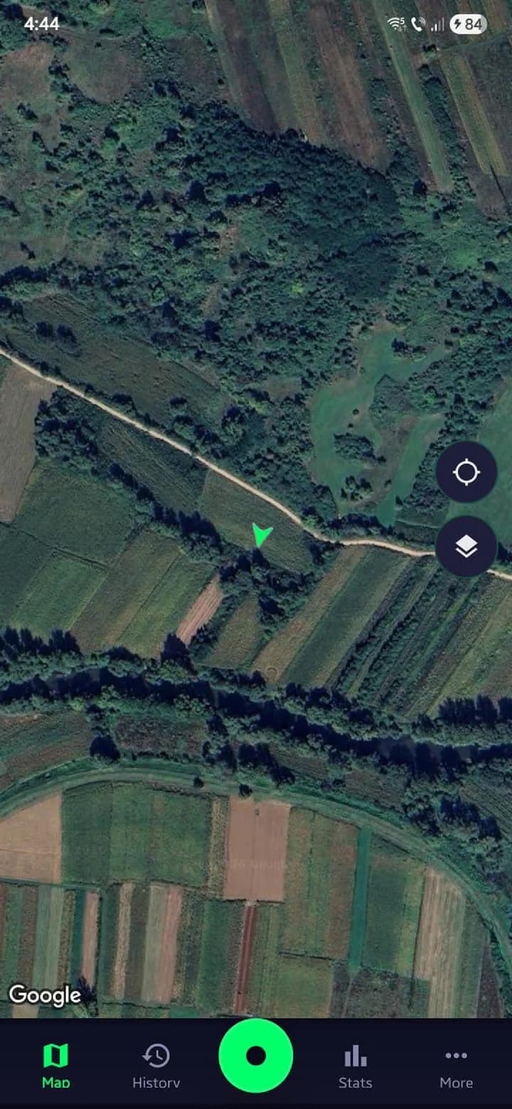 SweepTrack map screen: a satellite view of farmland with the user's green heading marker on a track, layer and centre controls at the right, and the record control in the centre of the bottom navigation bar.